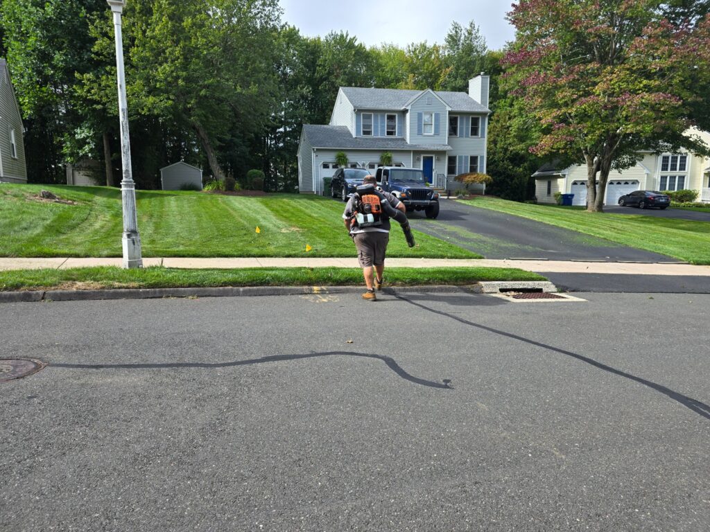 Worker using a leaf blower to clear grass clippings